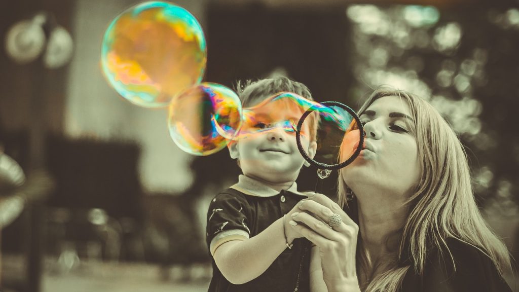 Une adulte et un enfant soufflant des bulles colorées, symbole de la douceur et du lien à La Cabane à Bulles